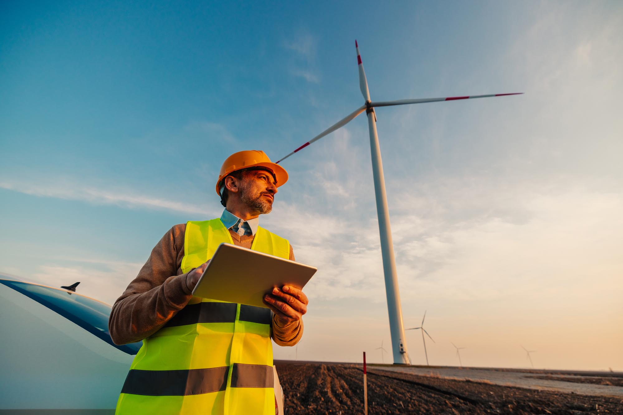 Engineer man looking and checking wind turbines at field